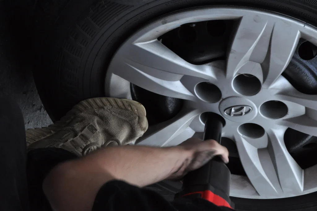 Mobile tyre fitter tightening wheel nuts with an impact wrench
